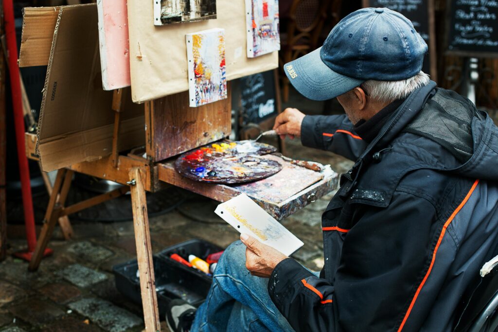 A street artist paints colorful abstracts on canvas, showcasing vibrant creativity in an outdoor setting.